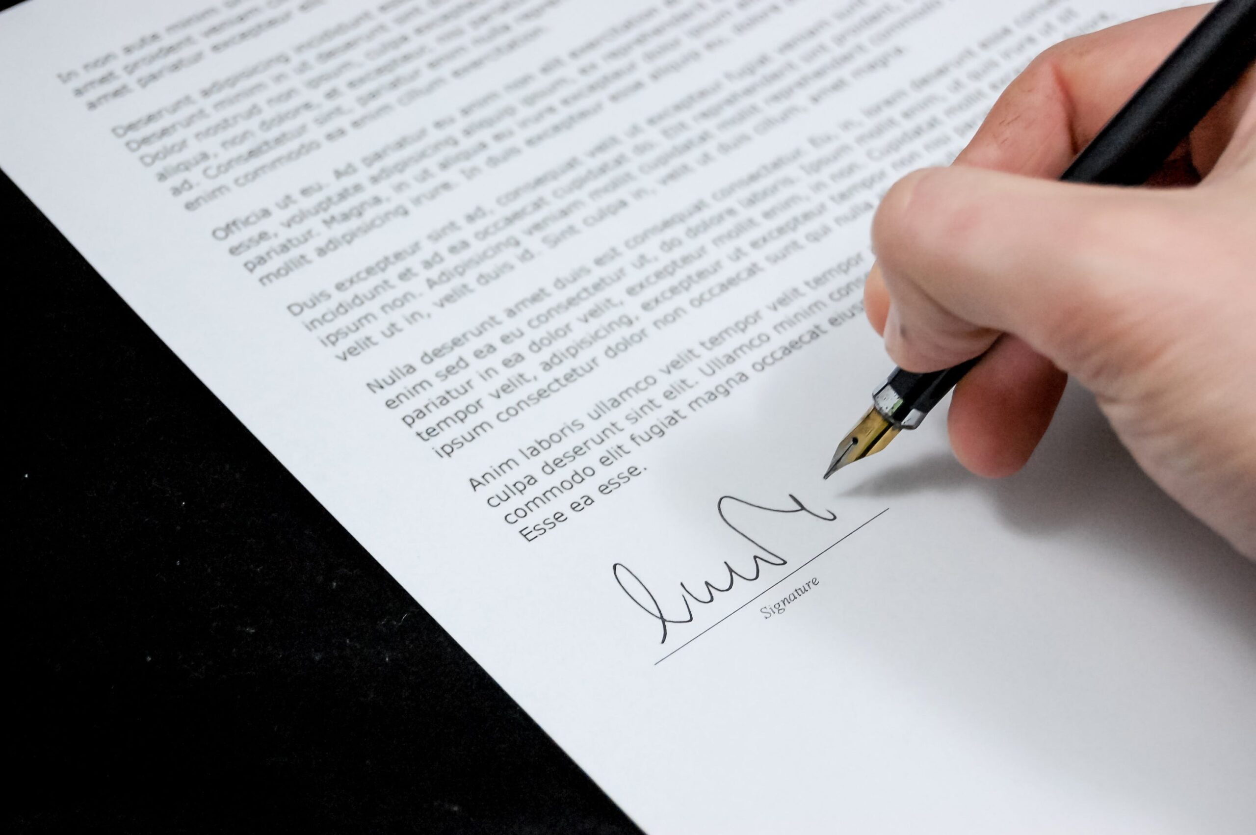 Mano firmando un documento con una pluma estilográfica