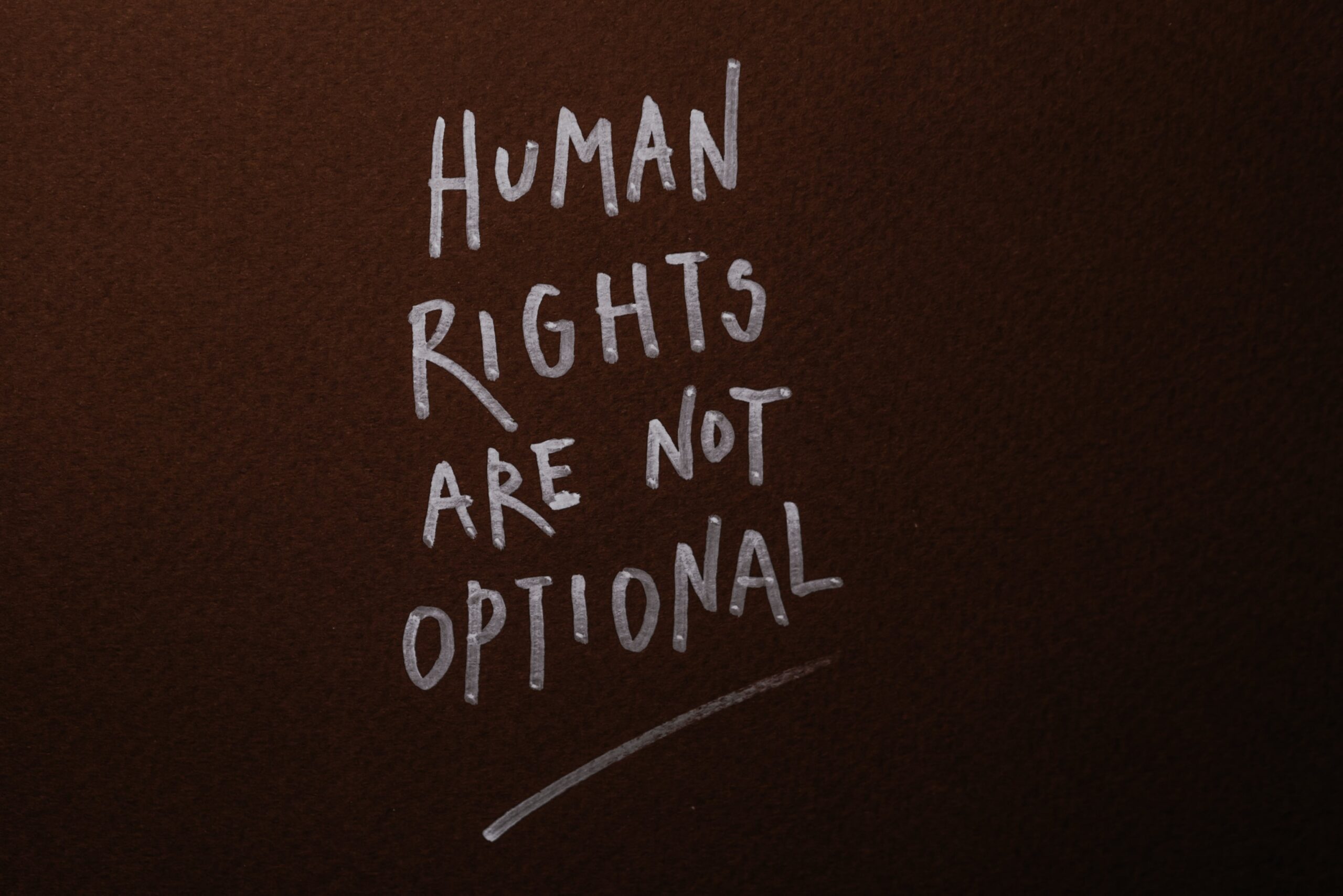 Texto blanco sobre fondo marrón que dice "Human Rights Are Not Optional"