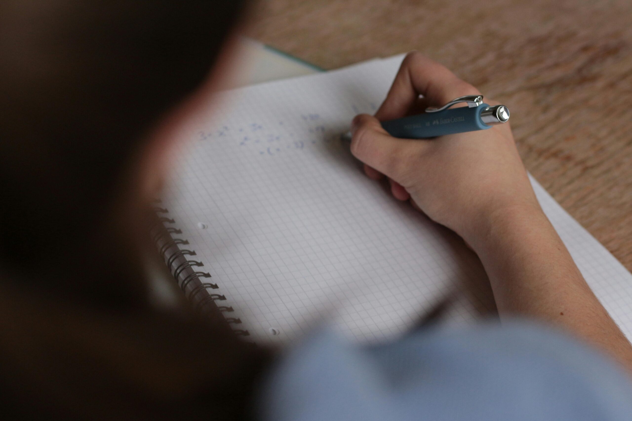 Persona escribiendo sobre una hoja que representa al examen de cemefi 